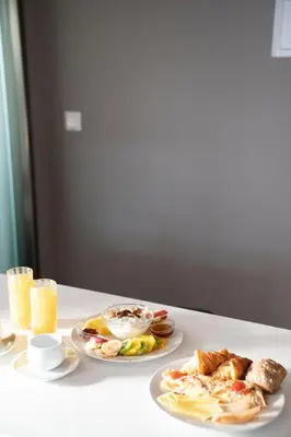a table with two plates of food and two glasses of orange juice at Chroma Fashion Rooms & Apartments in Athens