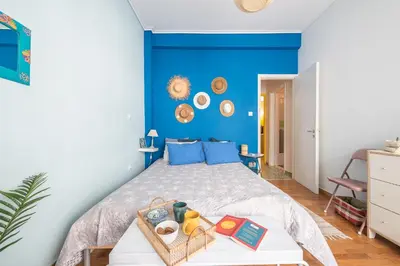 a bedroom with a bed with a blue wall at Sweet home in Koukaki in Athens