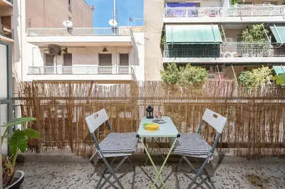 a table and chairs on a balcony with a fence at Sweet home in Koukaki in Athens