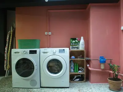 a laundry room with a washing machine and a pink wall at Miaouli8 in Athens