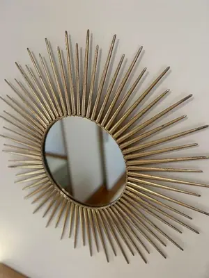 a gold sunburst mirror hanging on a wall at My Way Hotel in Athens