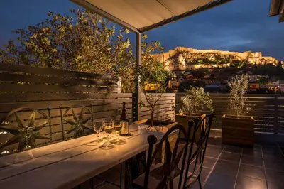 a wooden table with wine glasses on a patio at Fos Residential Apartments in Athens