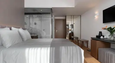 a bedroom with a large white bed and a bathroom at Elia Ermou Athens Hotel in Athens