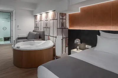 a bedroom with a tub and a bed and a chair at Elia Ermou Athens Hotel in Athens