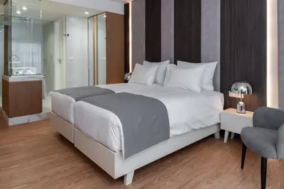 a bedroom with a large white bed and a bathroom at Elia Ermou Athens Hotel in Athens