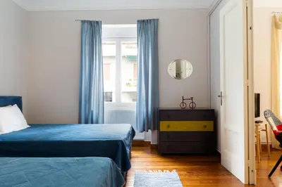 a bedroom with a bed and a window with blue curtains at M&N Koukaki House in Athens