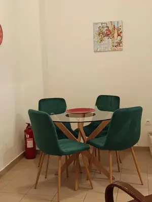 a table and four green chairs in a room at By Lycabettus in the city-heart close to Acropolis in Athens