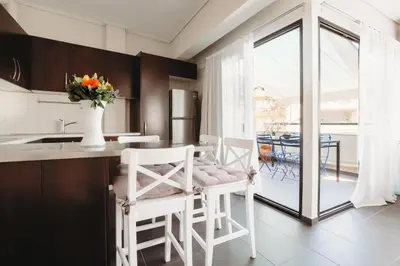 a kitchen with white chairs and a table with a vase of flowers at Athens Studios in Athens