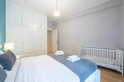 a white bedroom with a crib and a baby crib at Pame Rentals - 2BD & 2BA Home, 4 Min to Acropolis in Athens