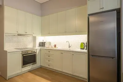 a kitchen with white cabinets and a stainless steel refrigerator at Pame Rentals - 2BD & 2BA Home, 4 Min to Acropolis in Athens