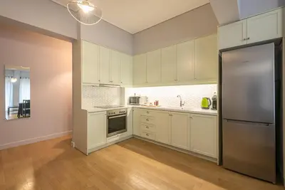 a kitchen with white cabinets and a stainless steel refrigerator at Pame Rentals - 2BD & 2BA Home, 4 Min to Acropolis in Athens