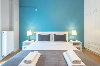 a bedroom with a large bed with a blue wall at Pame Rentals - 2BD & 2BA Home, 4 Min to Acropolis in Athens