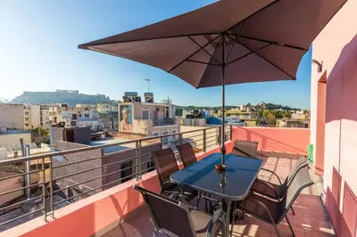 a table and chairs on a balcony with an umbrella at Central Stay Athens in Athens