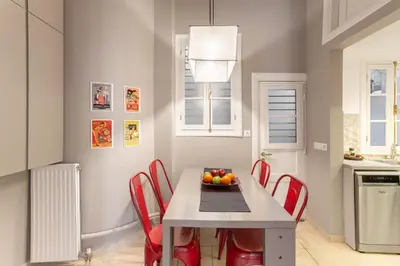 a kitchen with a table with red chairs and a bowl of fruit at Hidesign Athens Apollon Luxury Apt in Plaka Acropolis in Athens
