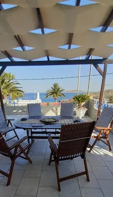 a patio with a table and chairs and the ocean at BLUE & WHITE MAISONETTE OVER THE SEA NEAR SOUNIO in Sounio