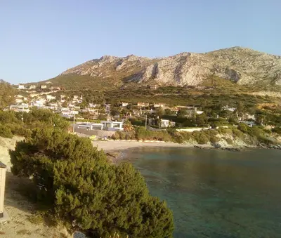 a view of a beach with houses and a mountain at BLUE & WHITE MAISONETTE OVER THE SEA NEAR SOUNIO in Sounio