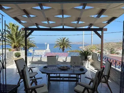 a patio with a table and chairs and the ocean at BLUE & WHITE MAISONETTE OVER THE SEA NEAR SOUNIO in Sounio