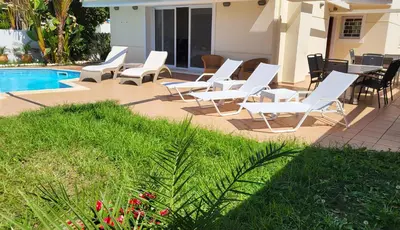 a group of white chairs and a swimming pool at Holiday villa SUNJOY close to the beach in Sounio