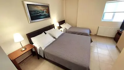 a small bedroom with a bed and a night stand with a lamp at Holiday villa SUNJOY close to the beach in Sounio