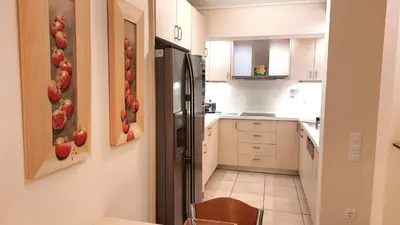 a kitchen with white cabinets and a black refrigerator at Holiday villa SUNJOY close to the beach in Sounio