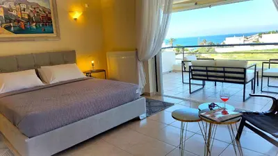 a bedroom with a bed and a balcony with a table at Holiday villa SUNJOY close to the beach in Sounio