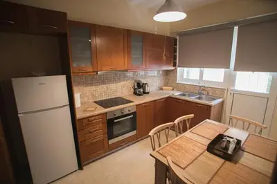 a kitchen with a white refrigerator and a table with chairs at Athenian Riviera Apartment in Athens