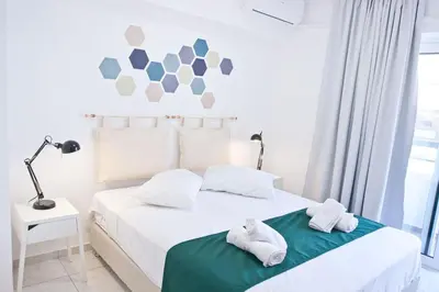 a white bedroom with a bed with towels on it at SilkFab Apartments in Athens