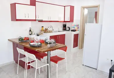 a kitchen with red and white cabinets and a table with chairs at SilkFab Apartments in Athens