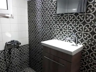 a bathroom with a sink and a black and white patterned wall at Mignon & Teak Apartments in Athens