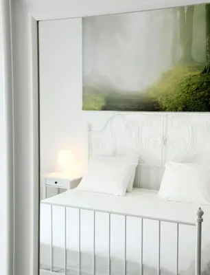 a bedroom with a white bed with a painting on the wall at Krezias Apartments E7 in Athens