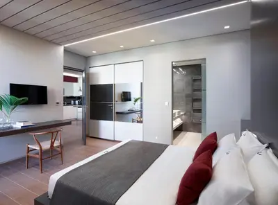 a bedroom with a bed and a desk and a kitchen at Athens Ikon in Athens