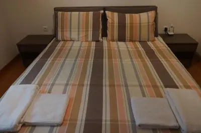 a bed with striped sheets and two towels on it at Georgina's cozy apartment -Metropolitan Hospital- in Piraeus