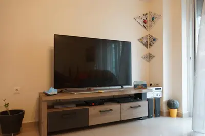 a flat screen tv sitting on top of a wooden entertainment center at Georgina's cozy apartment -Metropolitan Hospital- in Piraeus