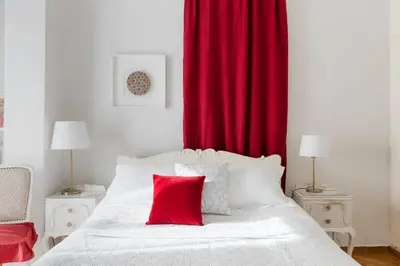 a bedroom with a white bed with a red curtain at Soulis' penthouse near Acropolis in Athens