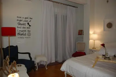 a bedroom with a bed and a chair and a window at Soulis' penthouse near Acropolis in Athens
