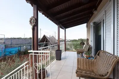 a porch with two wicker chairs on a balcony at Country Rooms near Athens - Airport in Vravrona