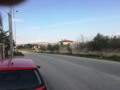 a red car parked on the side of a road at Country Rooms near Athens - Airport in Vravrona