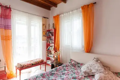 a bedroom with a bed and two windows with orange curtains at Country Rooms near Athens - Airport in Vravrona