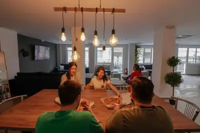 a group of people sitting around a table eating pizza at Athens Hawks in Athens
