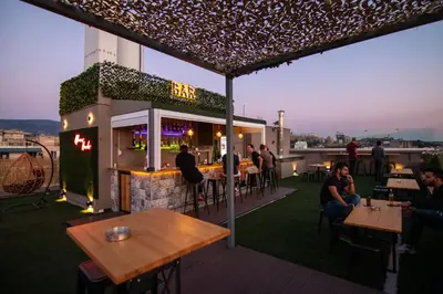 a rooftop bar with people sitting at tables on a roof at Athens Hawks in Athens
