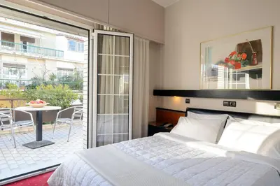 a bedroom with a bed and a balcony with a table at Victory Inn Hotel in Athens