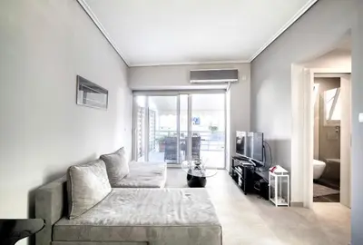a living room with a couch and a tv at Elea Athens Apartment in Athens