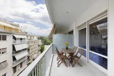 a balcony with a wooden table and chairs on it at Super modern minimal flat nr metro & arch. Museum in Athens