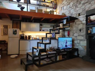 a living room with a tv and a stone wall at Live at the Acropolis shadow - under super scenic Anafiotika in Athens
