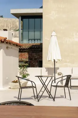 two chairs and a table and an umbrella on a patio at Acropolis Heights at the foot of the Parthenon in Athens