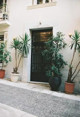a black door with potted plants in front of a building at Shila Athens in Athens