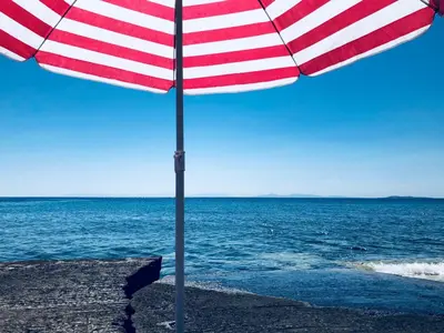a red and white striped umbrella on the beach at THE BOUCAMVIGLIA BEACH HOUSE in Saronida