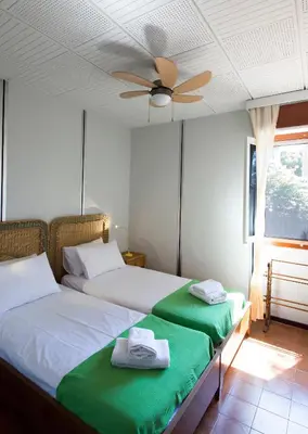two beds in a room with a ceiling fan at THE BOUCAMVIGLIA BEACH HOUSE in Saronida