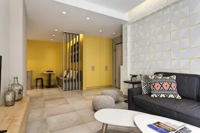 a living room with a couch and a yellow wall at Modern Design Acropolis Flat in Athens