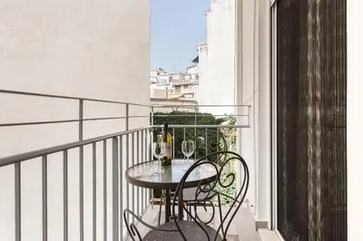 a table on a balcony with two glasses of wine at Modern Design Acropolis Flat in Athens